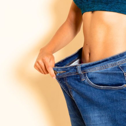 Une femme montre son jean trop grand après un régime.