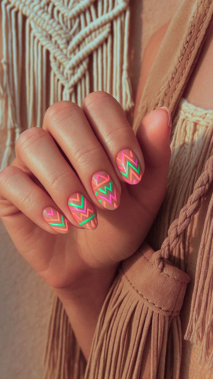 Motifs tribaux fluo rose et vert sur ongles nude, style bohème chic pour l'été